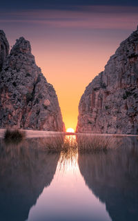 Reflection of rock formation in lake against sky during sunset