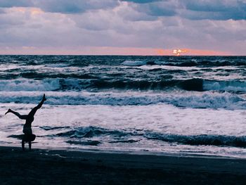 Silhouette man on beach against sky during sunset