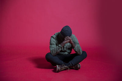 Man sitting against red background