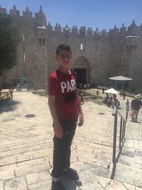 Portrait of boy standing against buildings in city