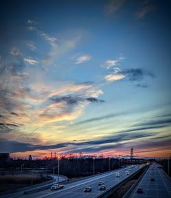 Cars on road against sky during sunset