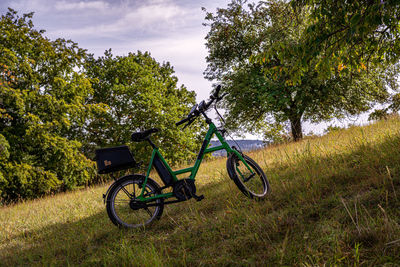 Bicycle on field by trees against sky