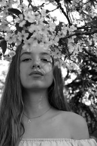 Portrait of teenage girl by flowers in park