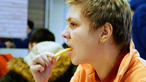 Close-up of woman eating french fries at restaurant