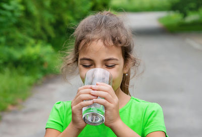 Young woman drinking water while standing outdoors