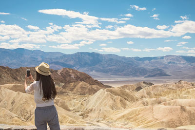 Rear view of woman photographing while rocky mountain