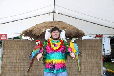 Portrait of smiling man with birds standing in tent