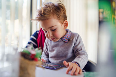 Boy looking away while sitting on table at home