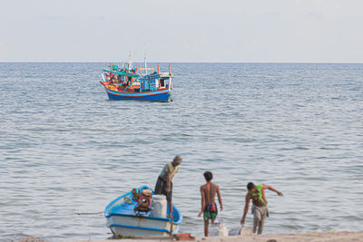 People working in sea against sky