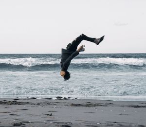 Man jumping over sea against sky