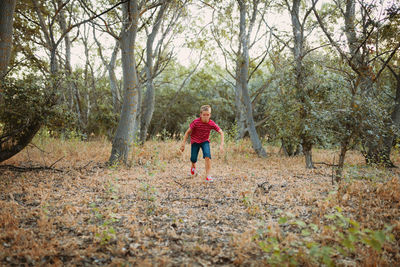 Full length of boy running in forest