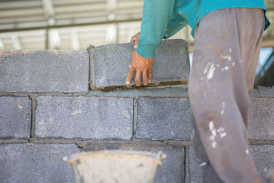 Low section of person working on concrete wall