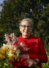 Older woman holding bouquet of fresh cut flowers in her garden