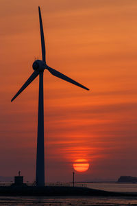 Silhouette of wind turbine against sky during sunset