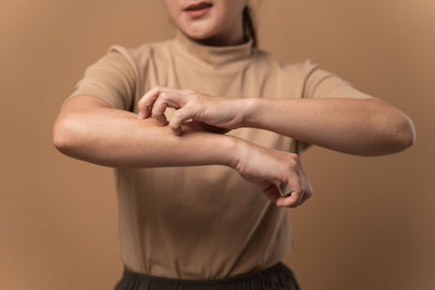 Midsection of woman gesturing against wall