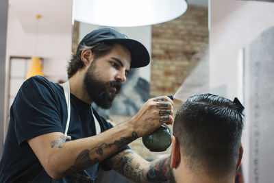 Hairdresser spraying water on customer's hair at barber's shop