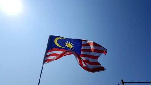Low angle view of malaysian flag against clear blue sky