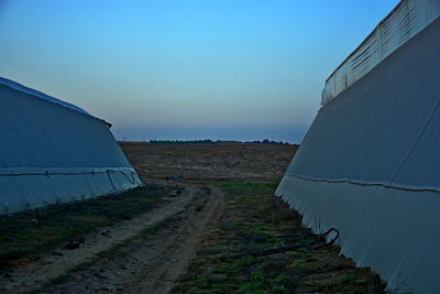 Road amidst field against clear blue sky