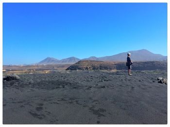 Rear view of man standing on mountain against clear sky