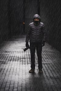 Full length of man walking on wet street during rainy season