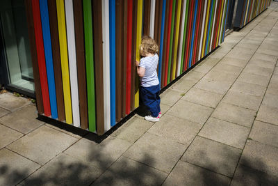 Rear view of boy standing against multi colored umbrella