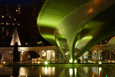 Illuminated bridge over river in city at night