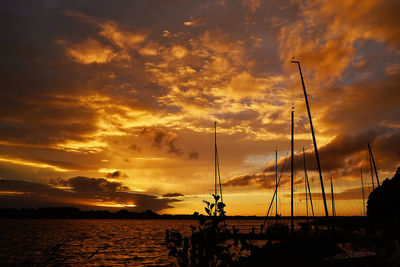 Silhouette sailboats on sea against dramatic sky during sunset