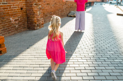 Rear view of woman standing against brick wall