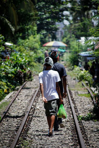 Rear view of boys walking on railroad track