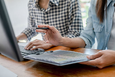 Midsection of woman using mobile phone while sitting on table