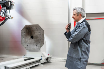 Worker examining machinery while standing in factory