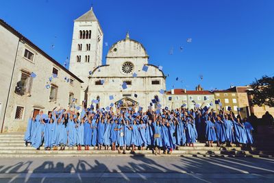 Group of students blue graduation gowns against cathedral