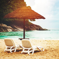 Chair on beach by sea against sky