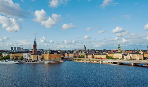 View of buildings by river against sky in city