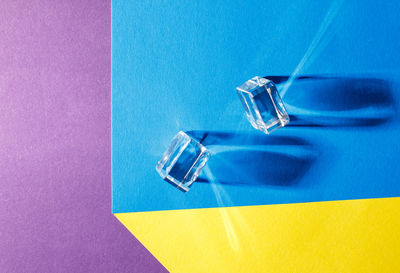 Two glass cubes on the colored table indoor closeup