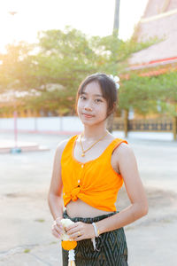 Portrait of young woman drinking water in park