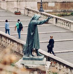 Rear view of people sitting on footbridge