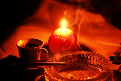 High angle view of lit candle by coffee and ashtray on table