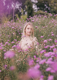 Woman standing on purple flowering plants on field