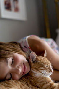 Close-up of girl sleeping with cat at home