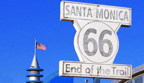 Low angle view of sign against blue sky