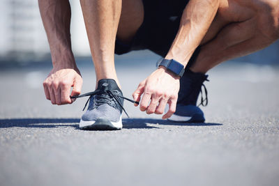 Low section of man tying shoelace