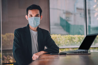 Portrait of businessman wearing mask sitting at office