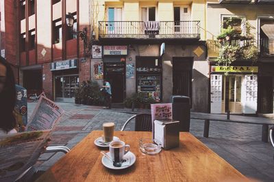 Chairs and tables in cafe against buildings in city