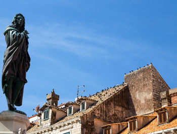 Low angle view of statue of building against blue sky