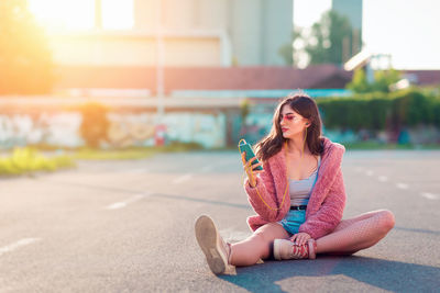 Portrait of young woman sitting on road in city