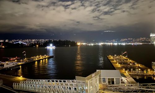 High angle view of illuminated buildings by river against sky