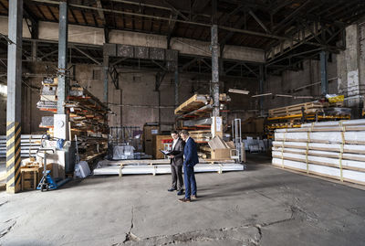 Two businessmen with folder talking in an old storehouse