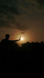 Silhouette man standing against sky during sunset
