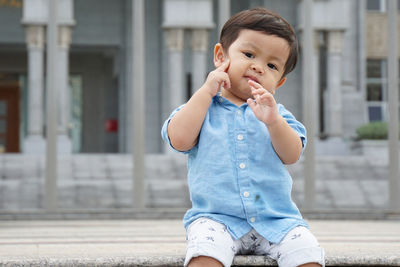 Cute boy looking away on street in city